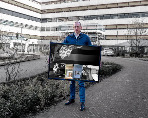 Een man staat met een fotolijst in zijn handen. 